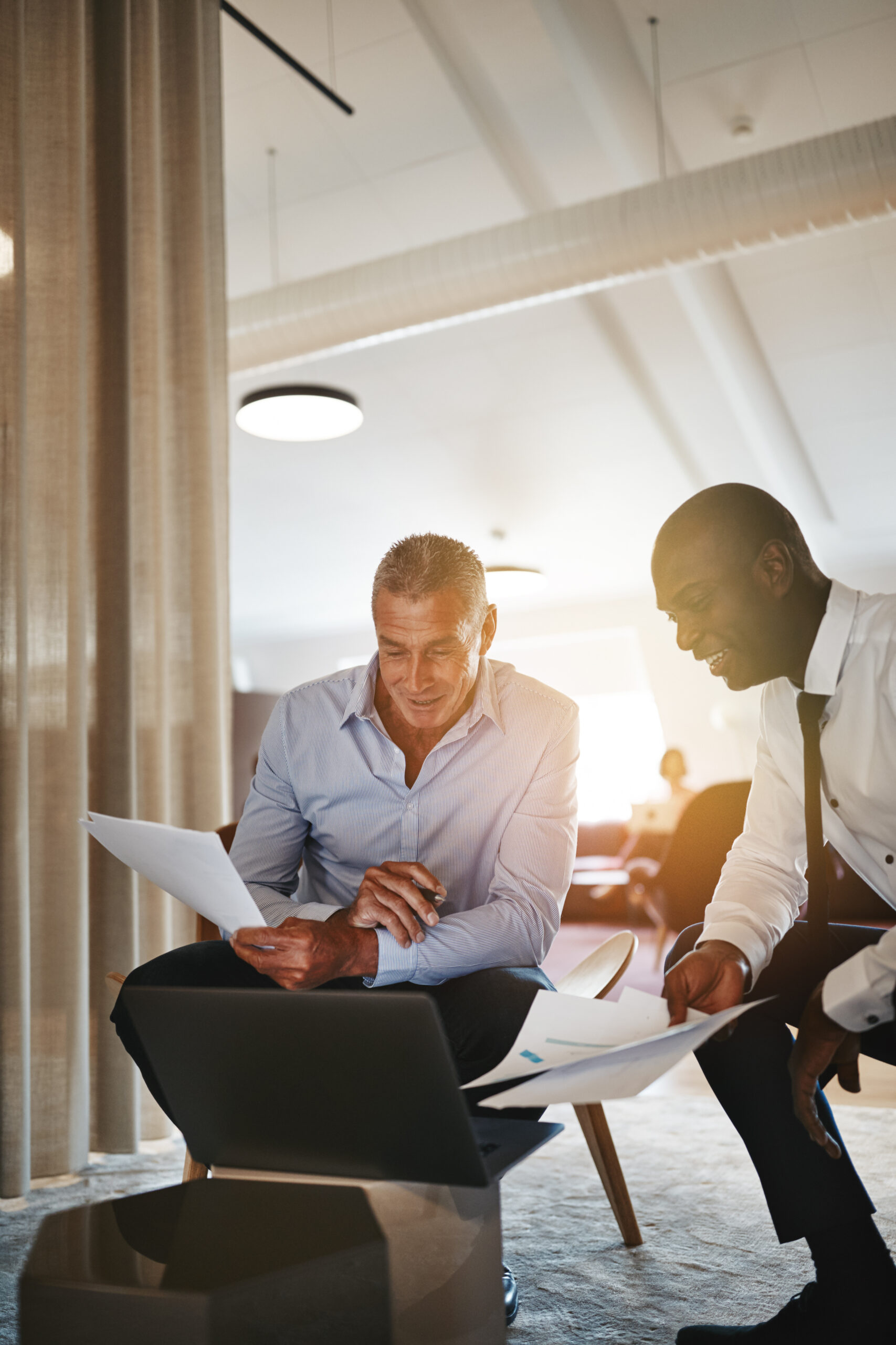 two men in suits in the office working on a laptop