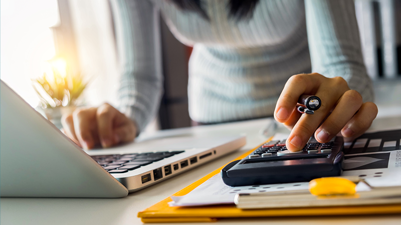 woman on her laptop and using a calculator